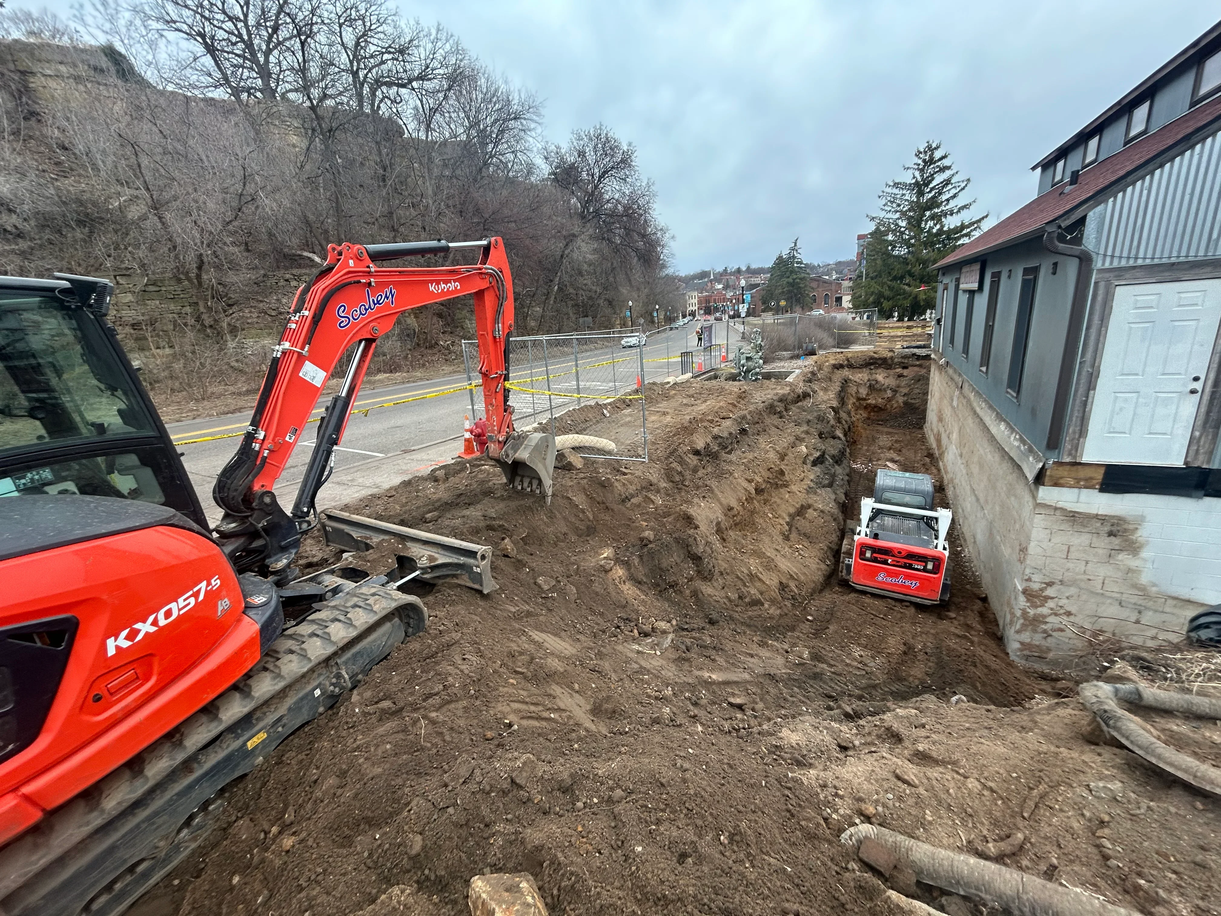 Red Kubota excavator and Scoley loader on residential excavation site in Hudson