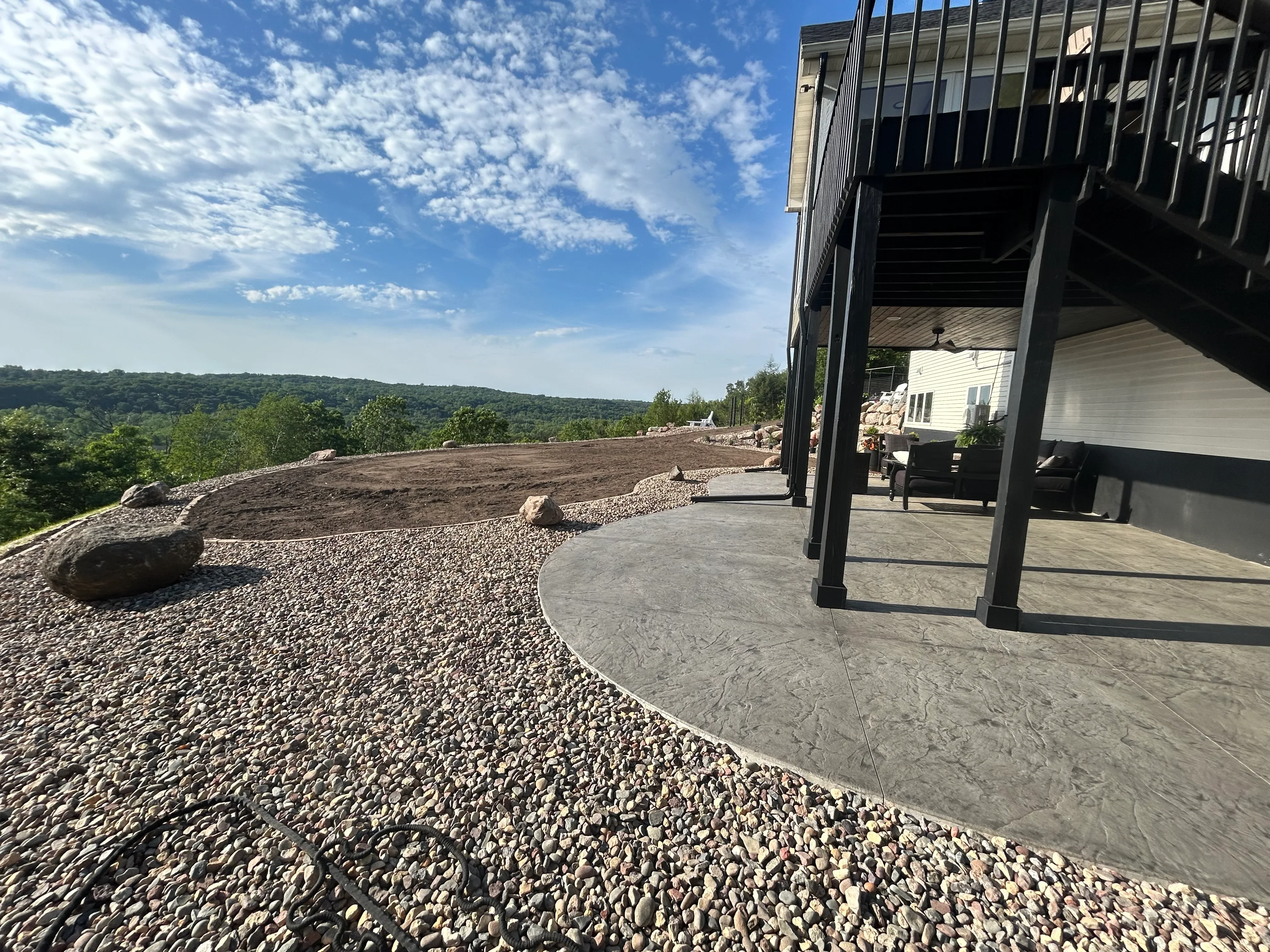 Hilltop excavation project with gravel landscaping, concrete patio, and valley views