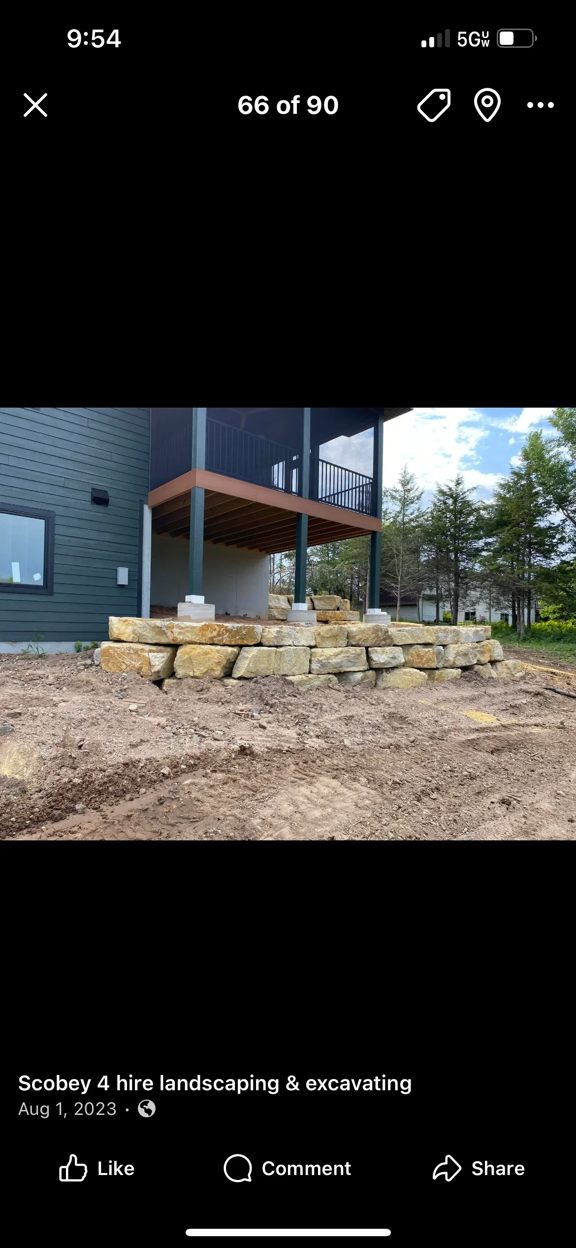 Stacked limestone retaining wall beneath elevated residential deck with metal railings
