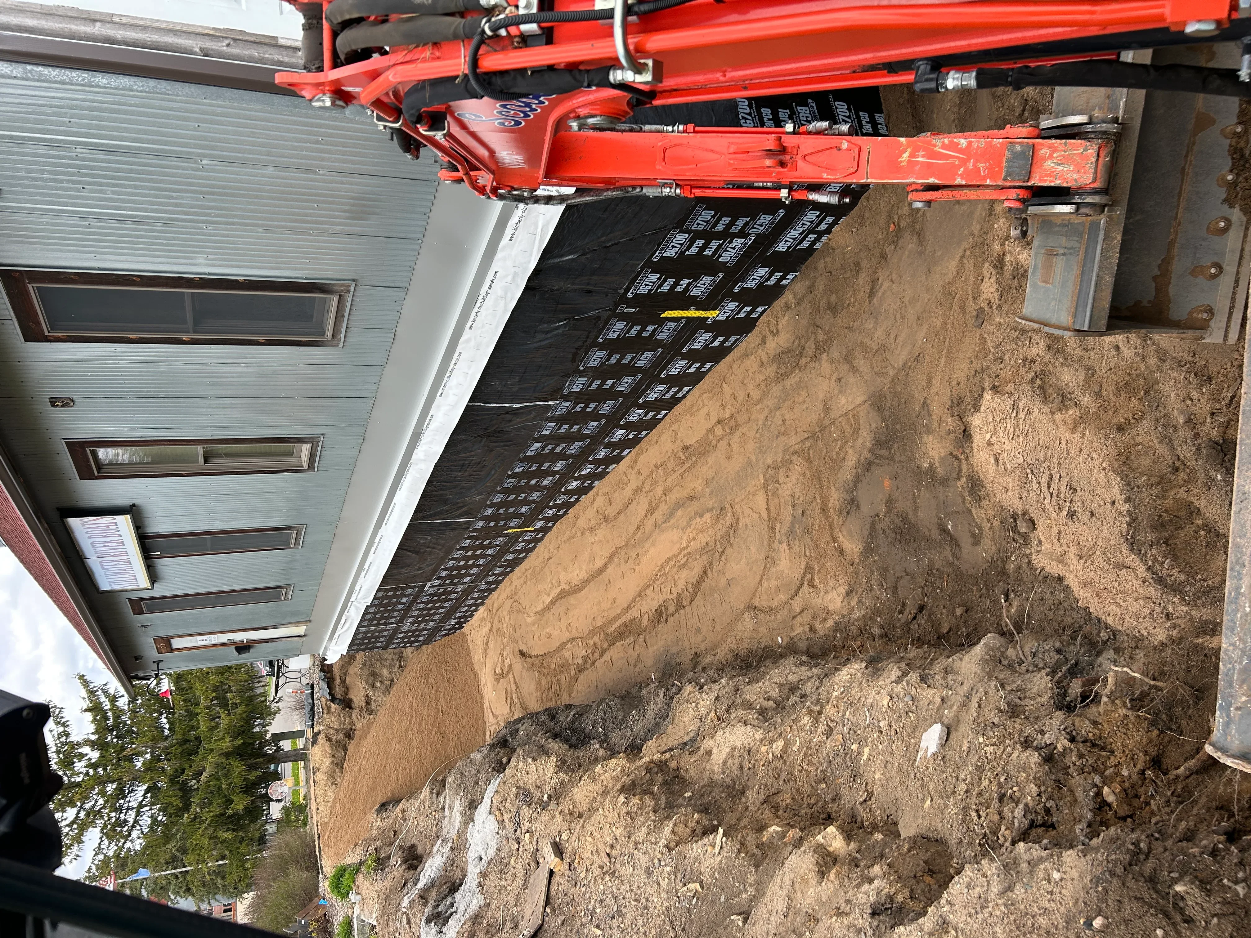 Red excavator on residential driveway site with compacted gravel base and prepared subgrade