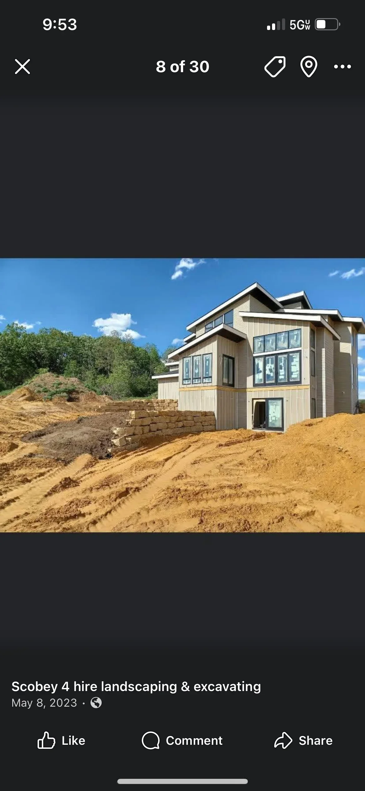 New home construction site with excavated lot, retaining wall, and graded earth