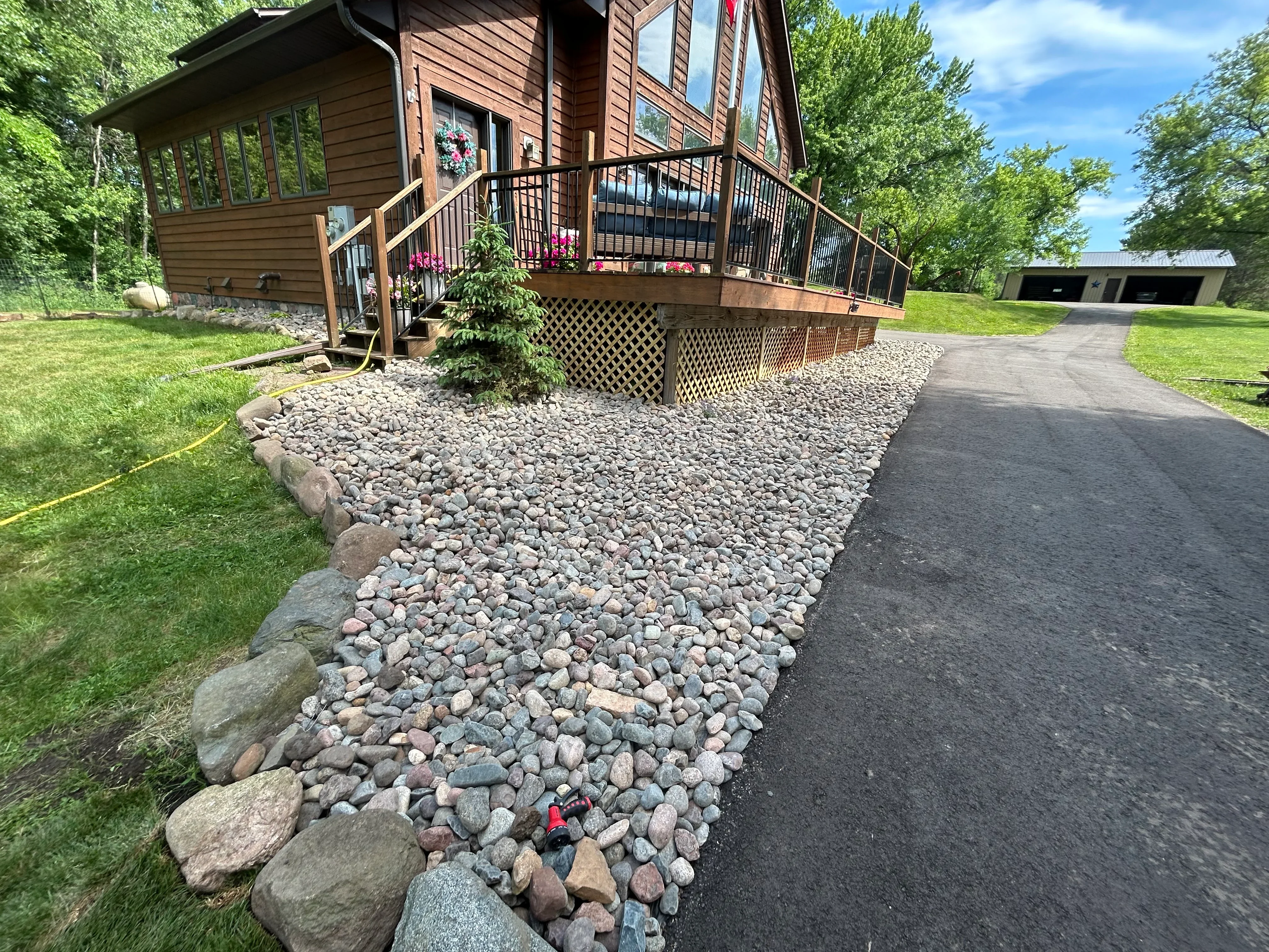 Residential driveway with river rock landscaping and stone edging around home foundation