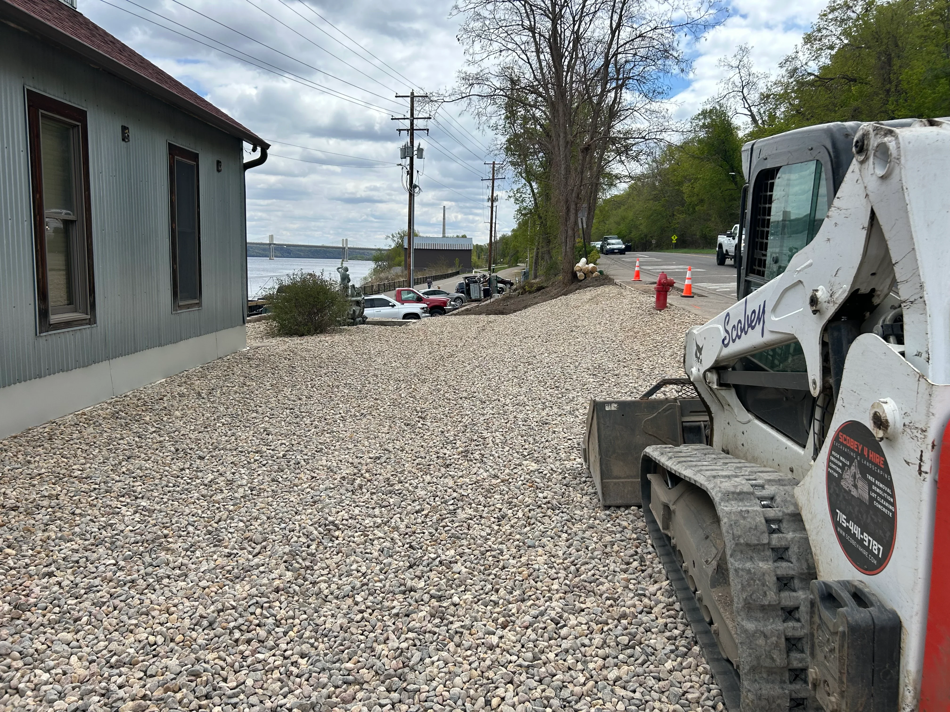 Excavation equipment on prepared gravel lot with waterfront view and commercial building