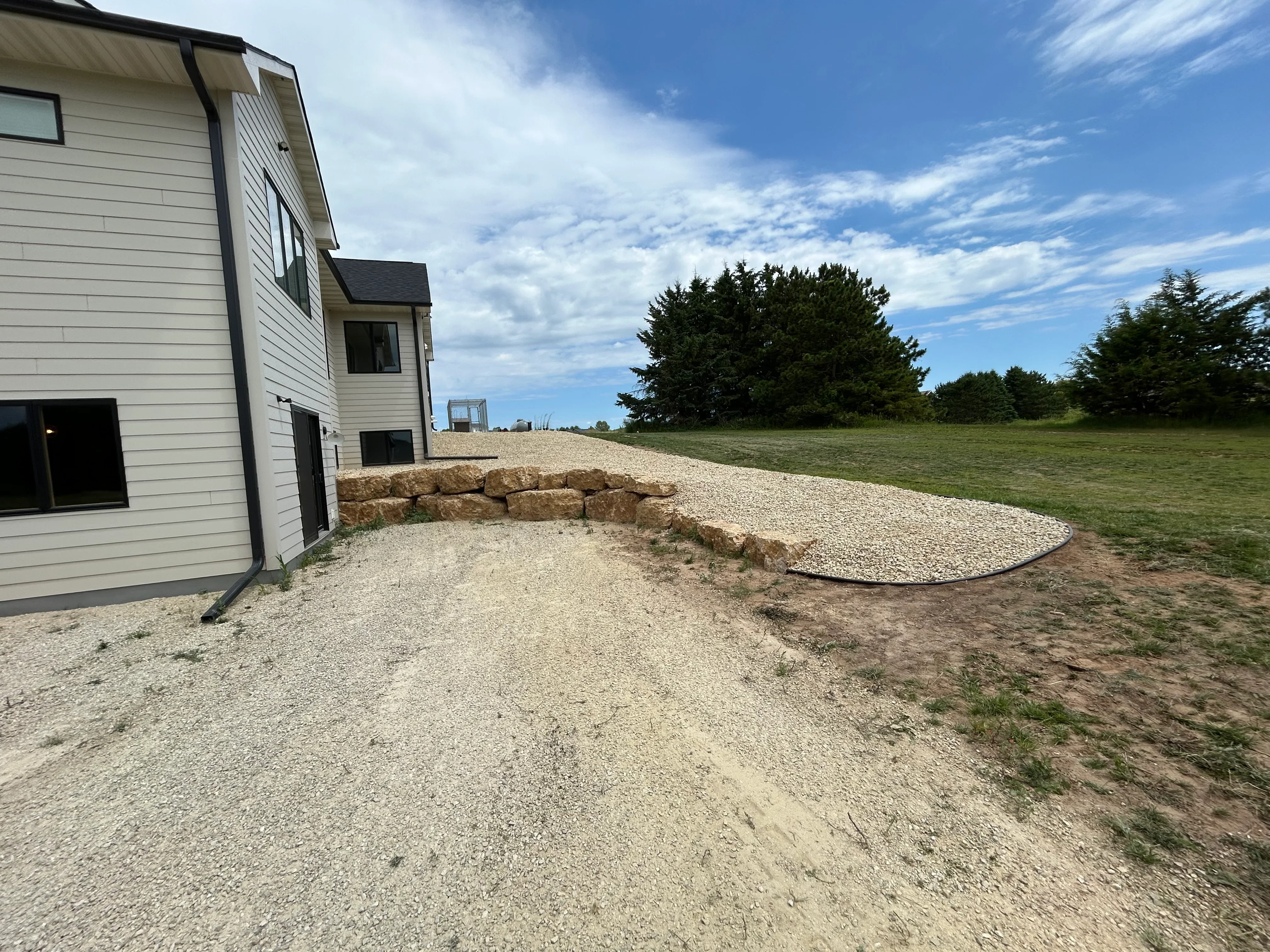 Gravel driveway with stone retaining wall beside modern home in Hudson, WI