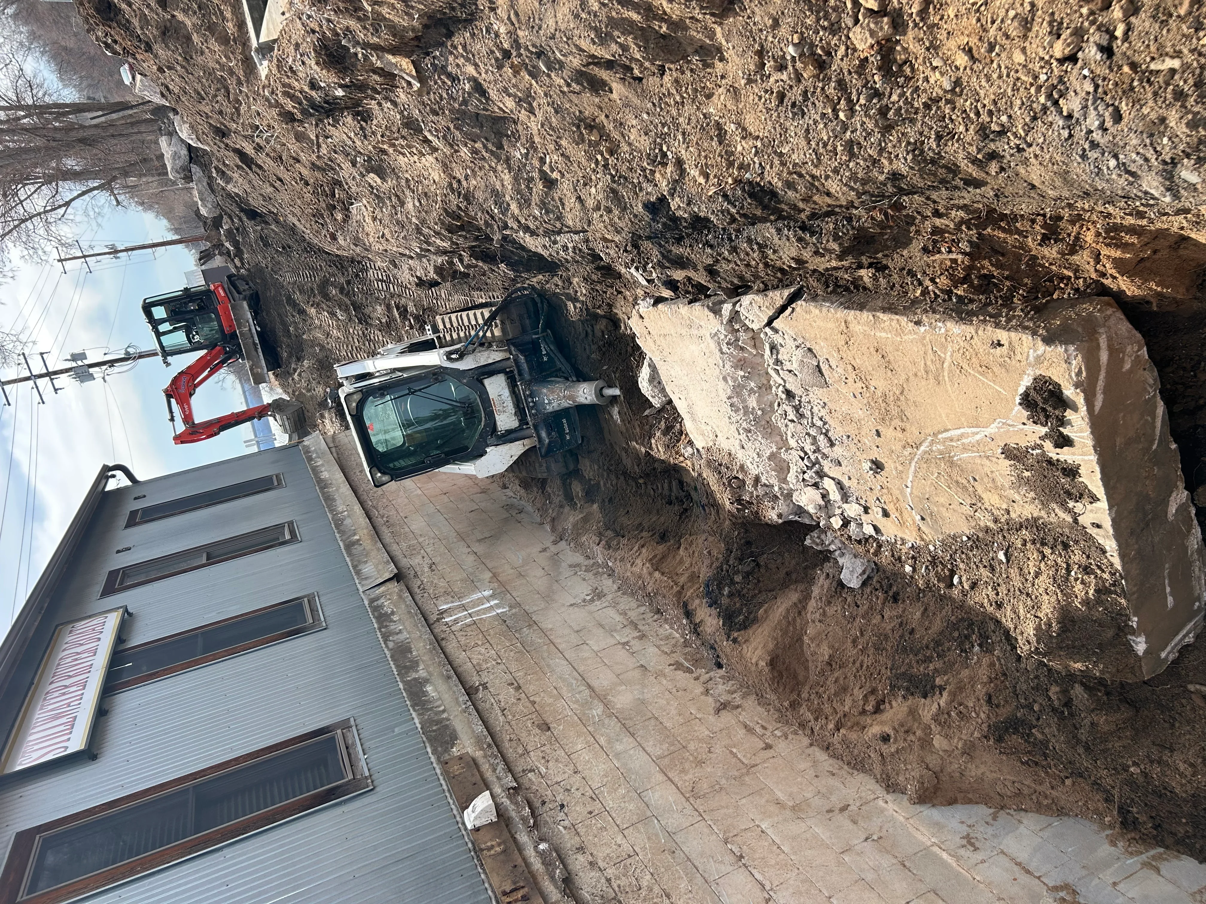 Excavation site showing deep soil removal and grading work near residential home