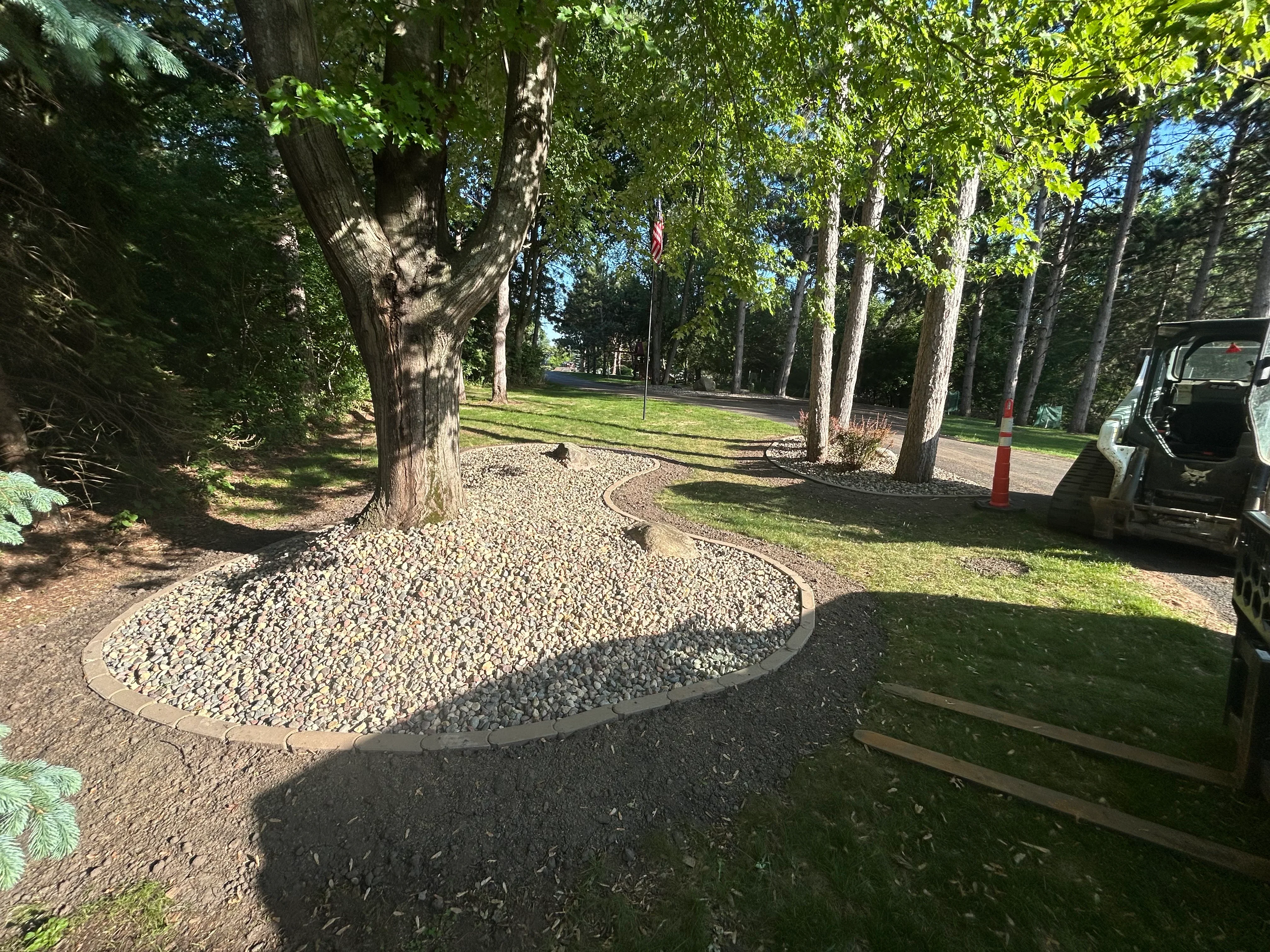 Gravel driveway with metal edging installed among mature trees in wooded residential setting