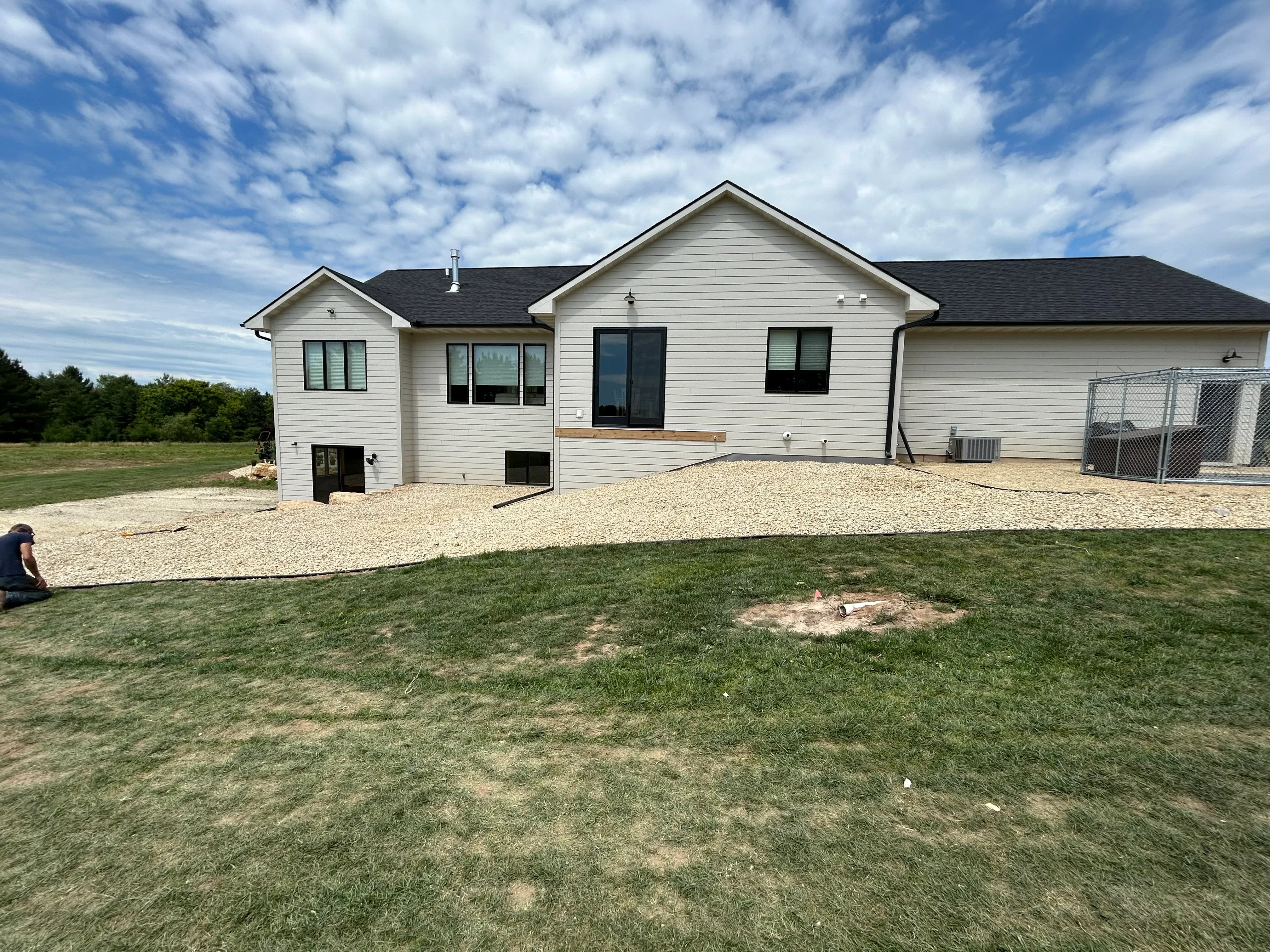 White vinyl-sided home with gravel driveway and excavated site preparation