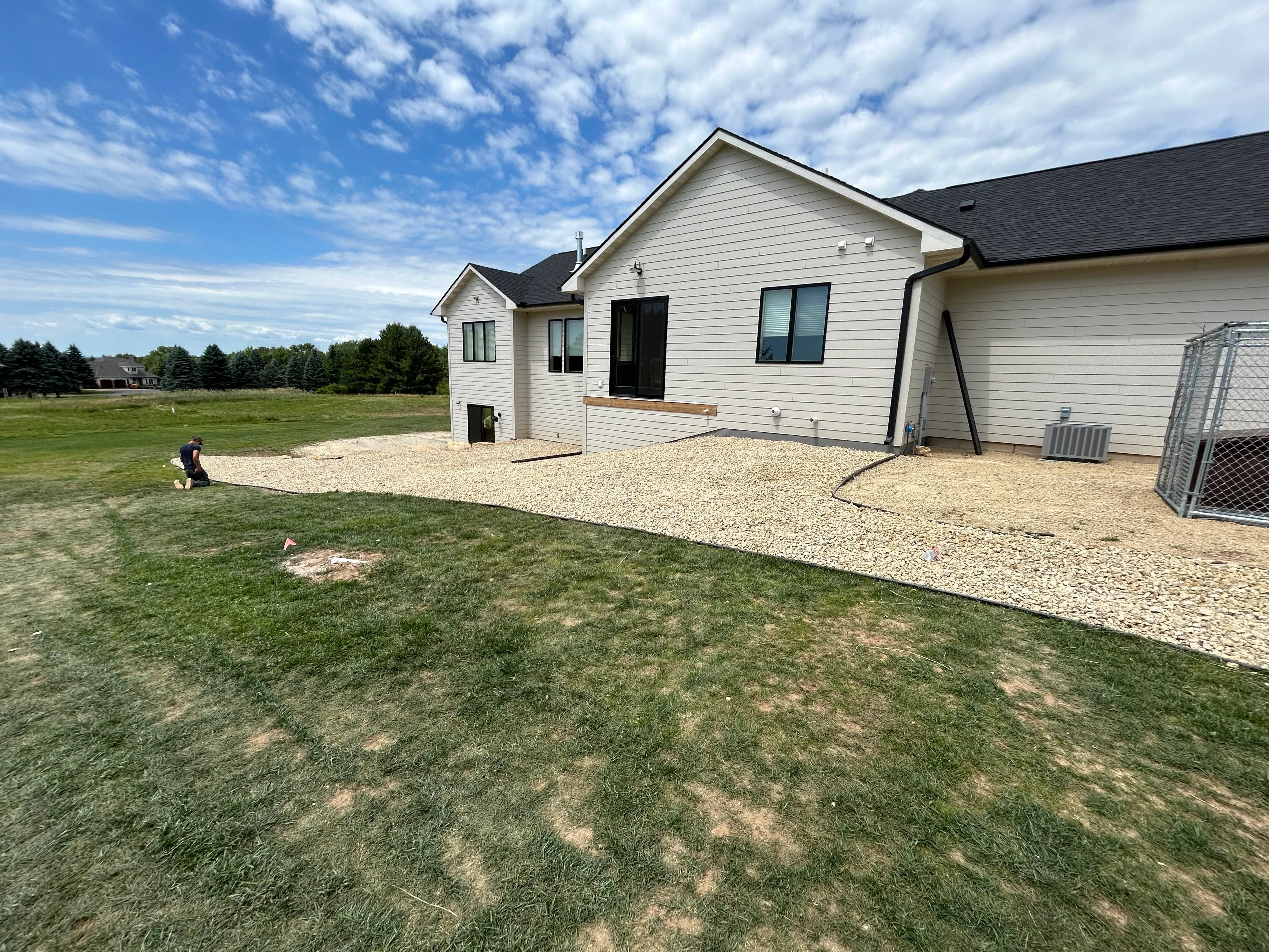 White residential home with newly excavated crushed stone driveway and patio area