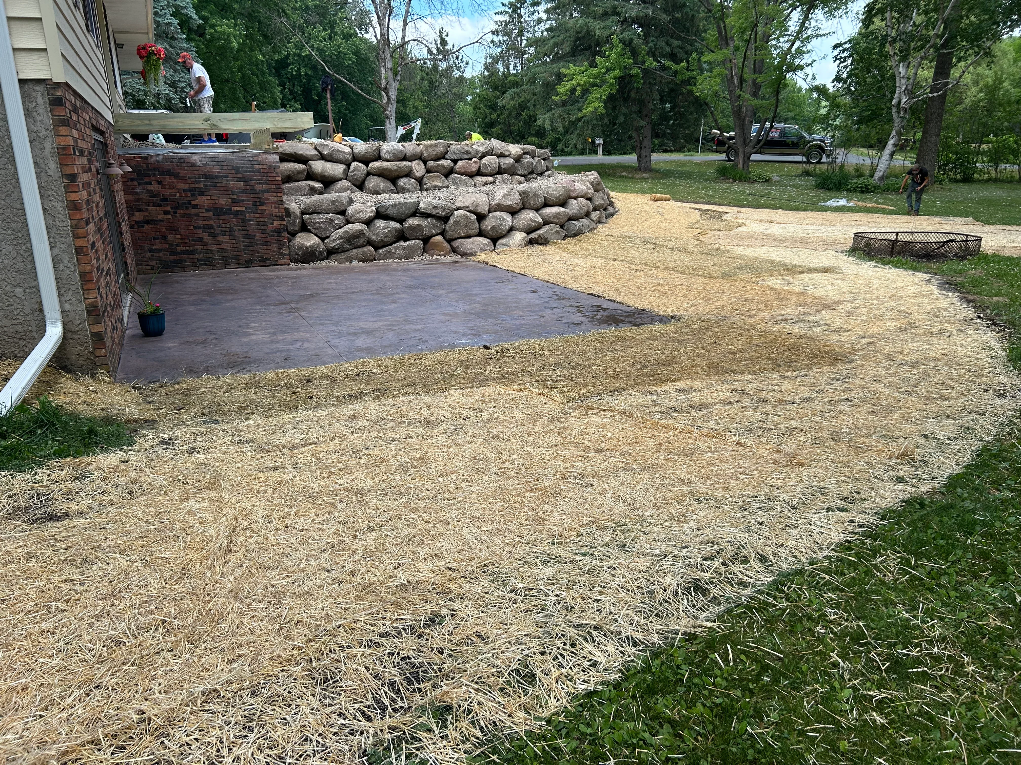 Residential yard with stacked stone retaining wall and freshly graded mulch landscaping