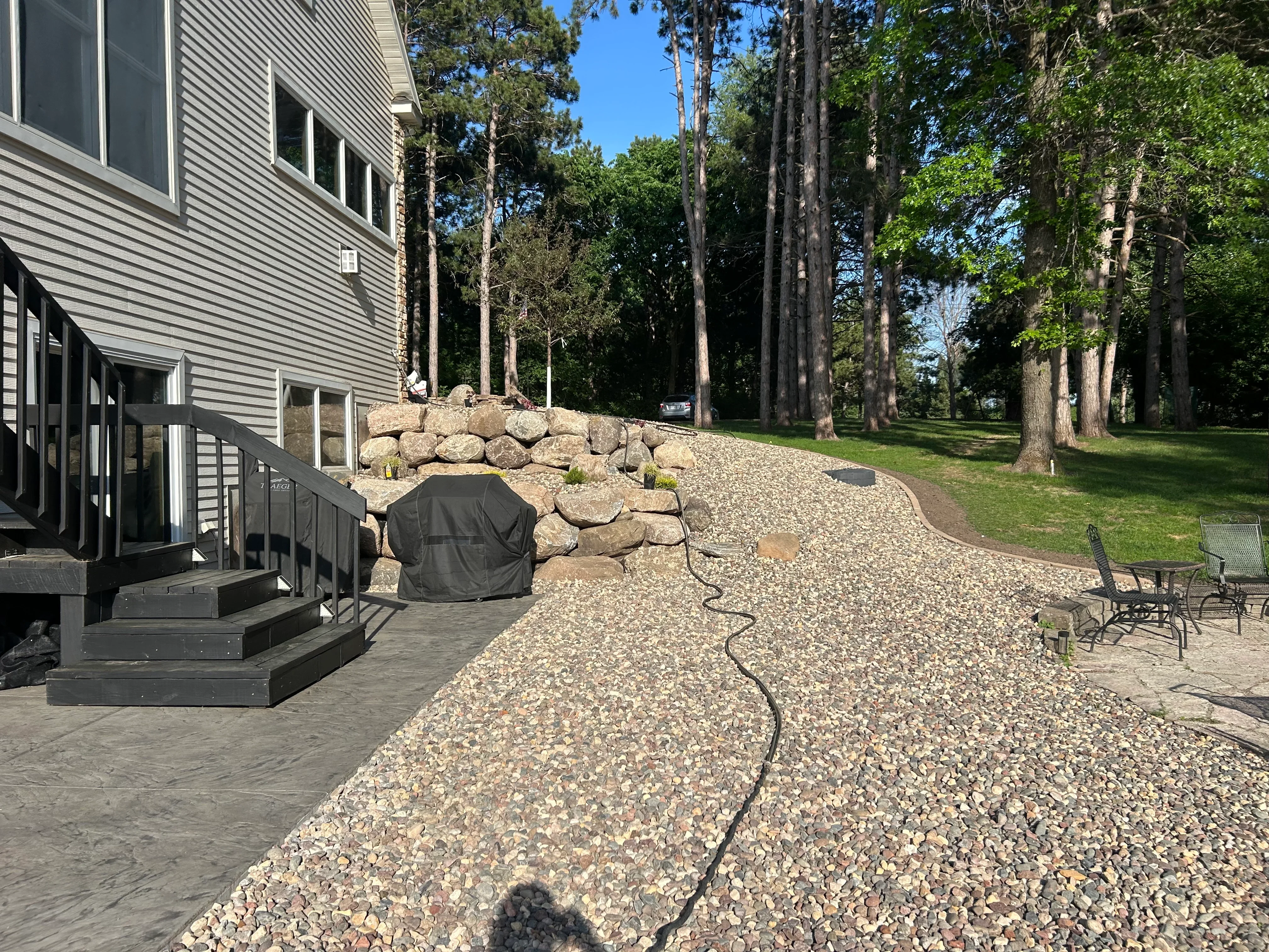 Gravel driveway with stacked stone retaining wall beside residential home