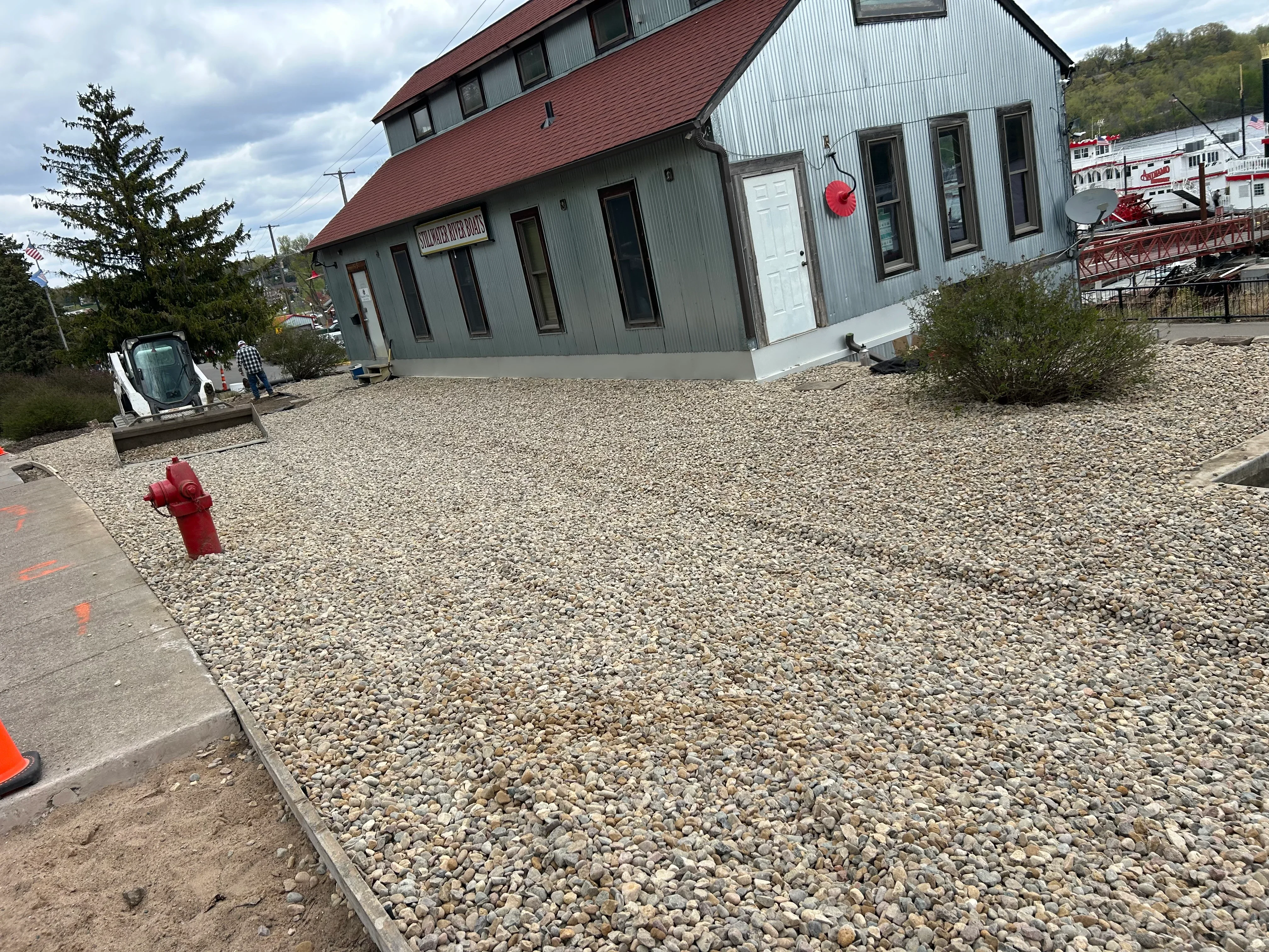 Finished gravel lot with crushed stone base next to gray commercial building with red roof